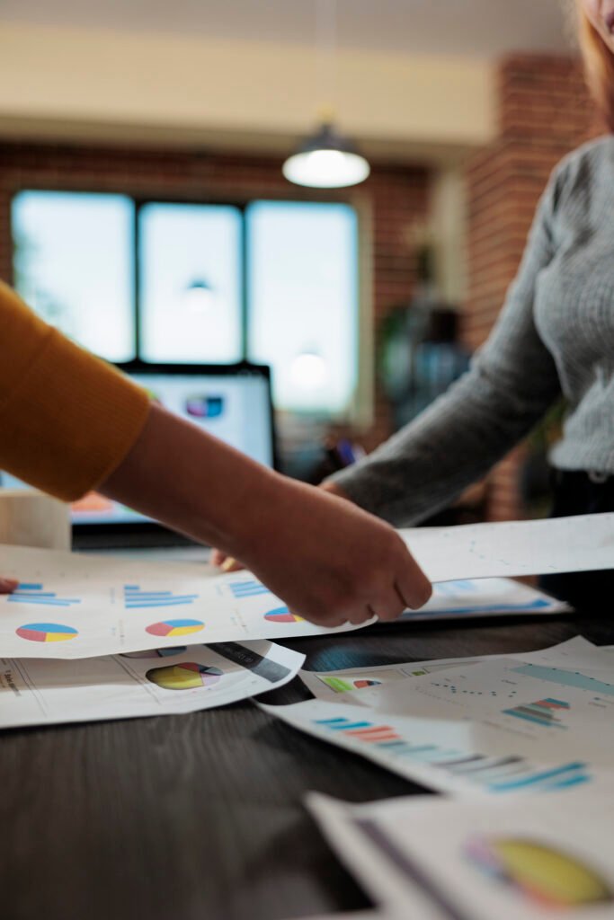 Close up of women entrepreneur holding papers with company statistics working at marketing project in startup office. Executive managers planning business meeting to discuss management strategy